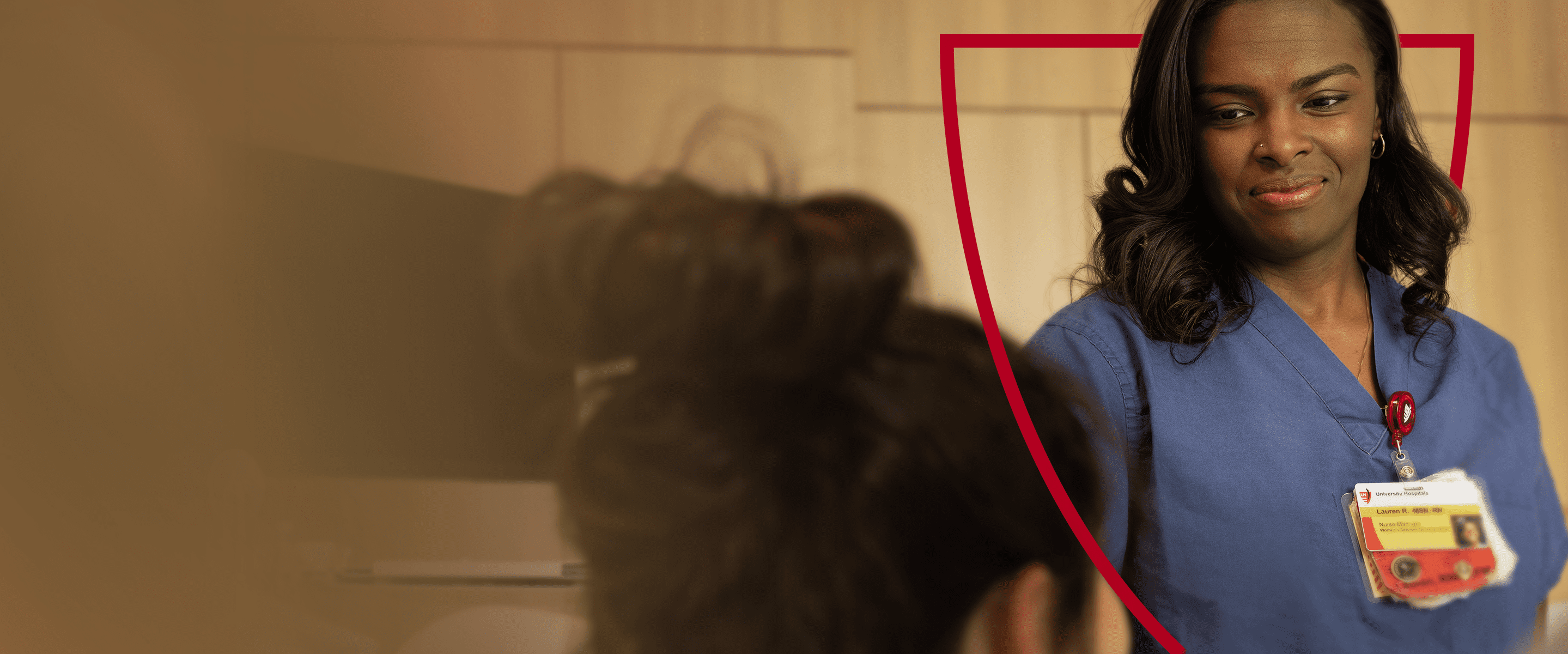 A smiling nurse in blue scrubs interacting with a patient.