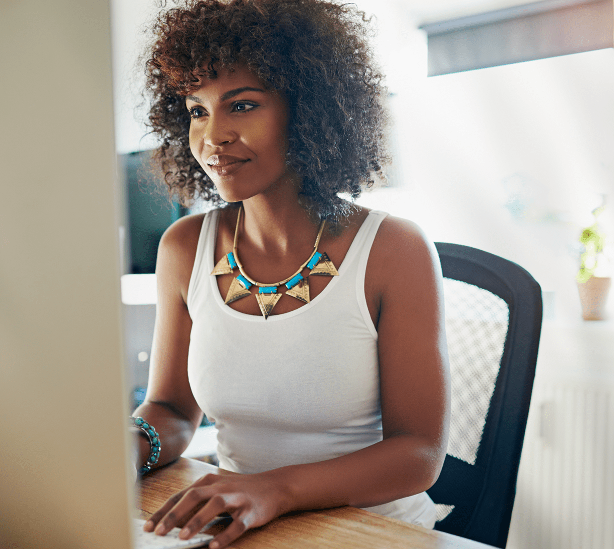 54f50426530db5c33b9b32b954a5df54dfda6ab9 A woman working at a desk focuses on her computer in a bright and modern workspace