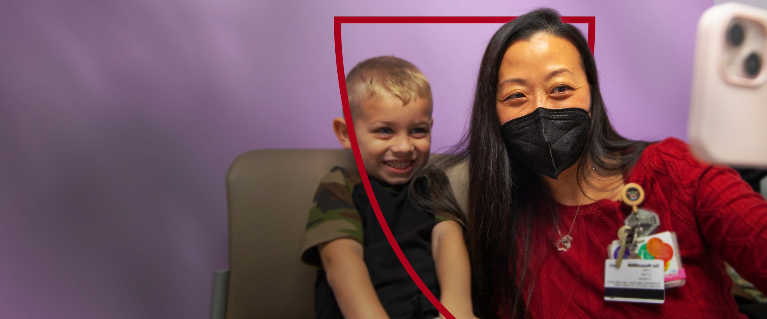 A masked healthcare professional smiling with a young patient.
